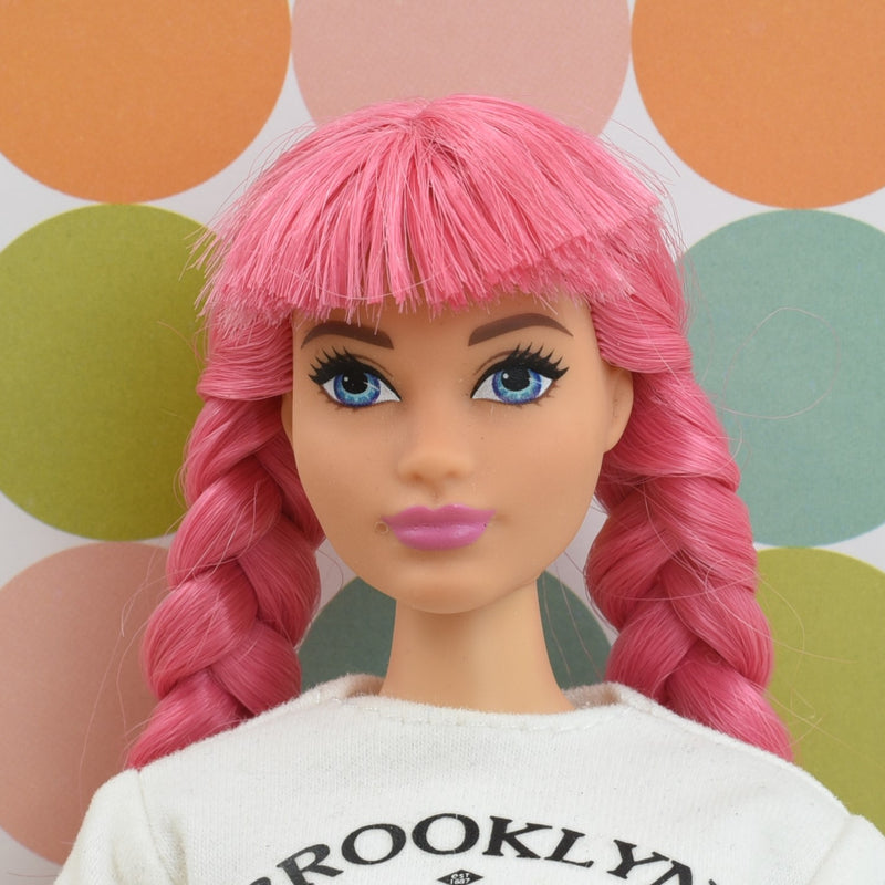 Headshot of a curvy Barbie doll with pink hair named Daisy