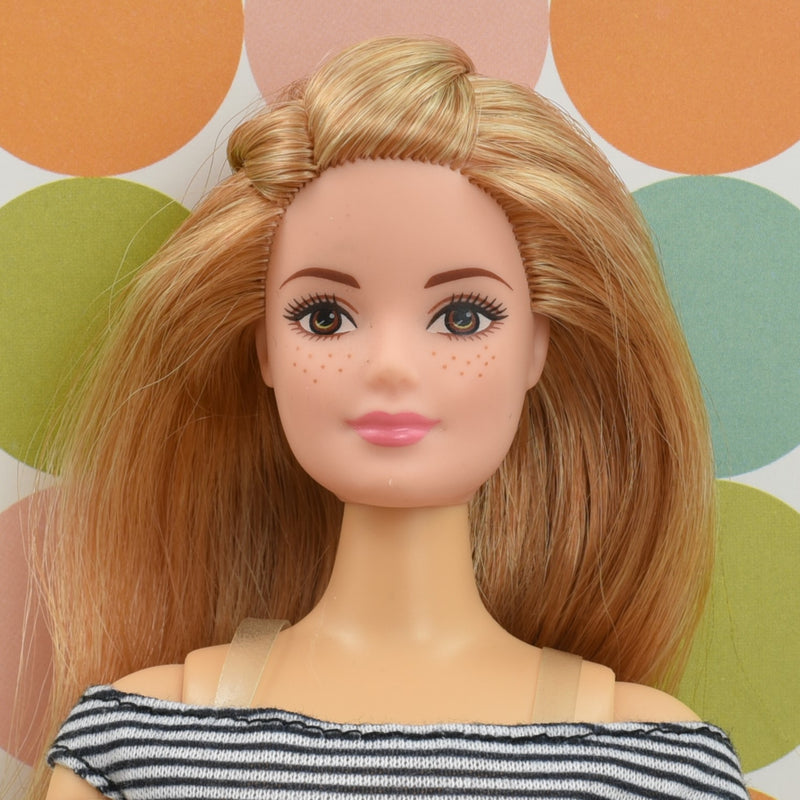 Headshot of a curvy Barbie doll with blonde hair named Barbie