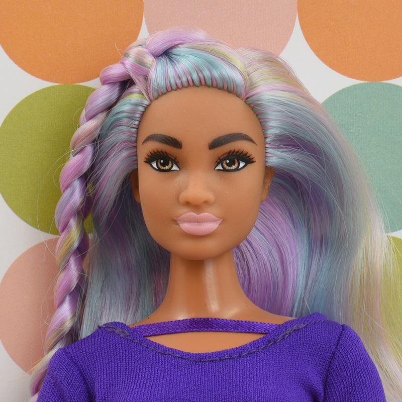 Headshot of a curvy Barbie doll with rainbow hair named Harmony