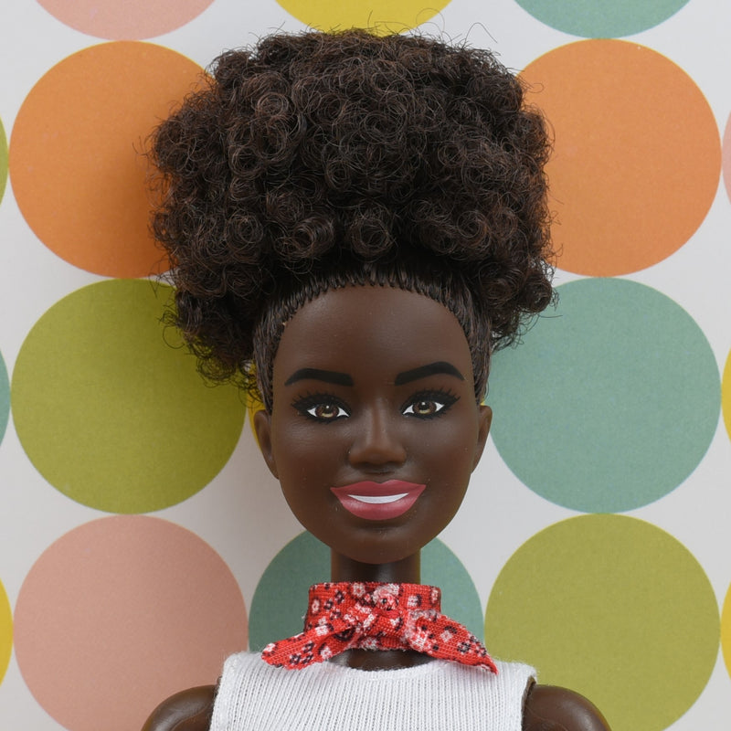 Headshot of a Barbie doll with brown afro hair named Aliyah