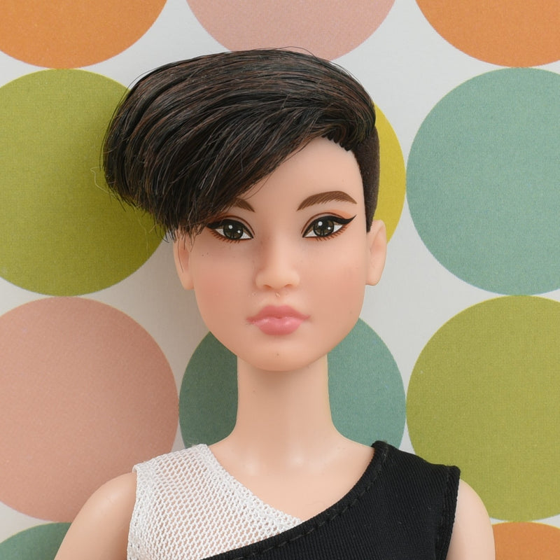 Headshot of a petite Barbie doll with black hair named Alex