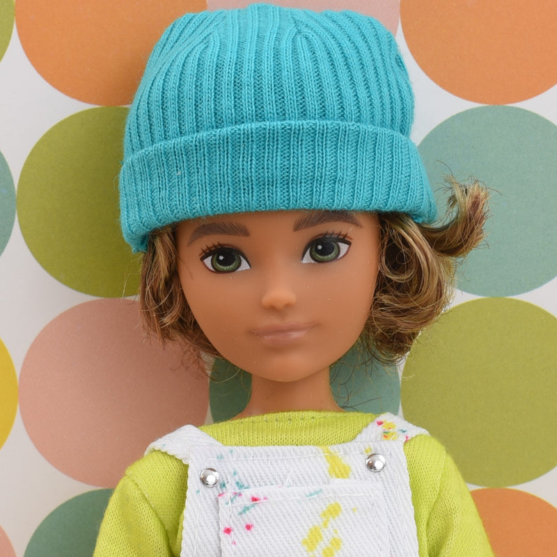 Headshot of a Creatable World doll with curly hair and a stocking cap named Mini G